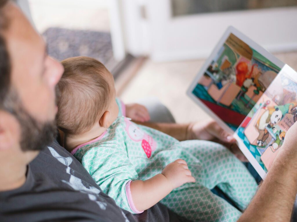 photo of dad reading book to baby