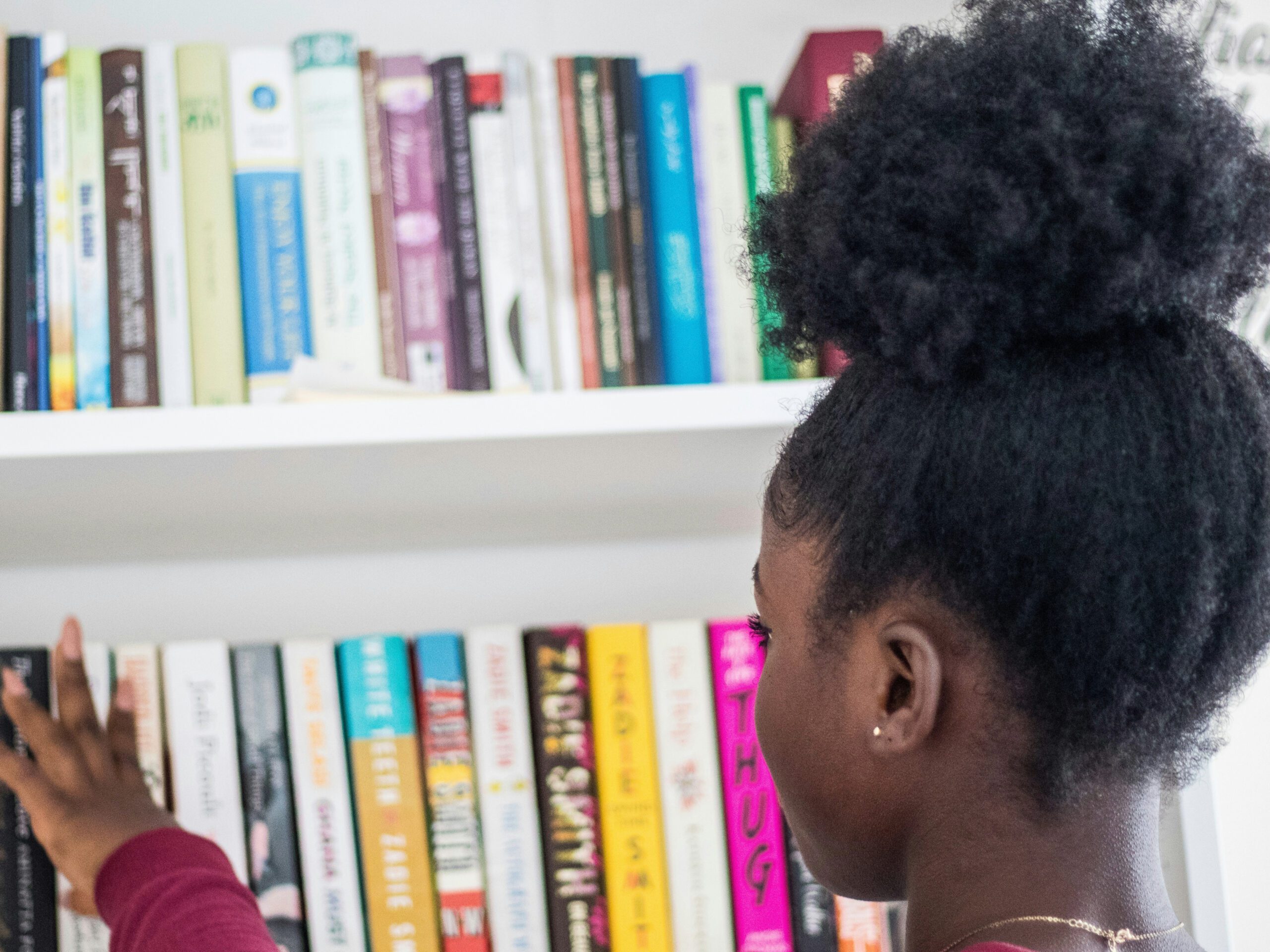 young girl browsing bookshelf filled with books